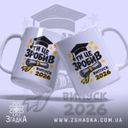 Чашка для випускника. Білий фон, ракурс з двох боків, на обох чашках великий напис "ТИ ЦЕ ЗРОБИВ" чорного кольору, під ним зображення диплома та напис "випуск 2026" жовтого кольору. Ручки круглі, краї рівні, глянцеве покриття.