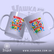 Чашка для здачі НМТ, дві білих чашки, розташовані під кутом одна до одної, кольоровий принт з текстом на обох чашках, ручки класичної форми, край рівний, глянцева поверхня.