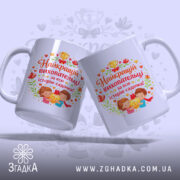 Чашка найкращій виховательці садочку, біла з кольоровим принтом, ракурс з двох боків, фон світло-фіолетовий, на принті зображення дітей з медаллю, текст червоним кольором, ручки обидві видні, край рівний, глянцева поверхня.