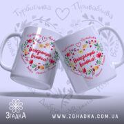 Чашка Найкращий Вчитель, дві чашки з кольоровим принтом, показані під кутом, на фоні світло-фіолетового кольору, з написом "Найкращий вчитель!" в центрі, оточеним квітами і сердечками, ручки класичні, краї рівні, глянцеві.