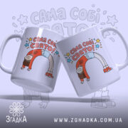 Чашка Сама собі свято, біла, зображена з двох боків, на фоні світло-фіолетового кольору, з кольоровим принтом, що містить напис "САМА СОБІ СВЯТО!" та малюнок дівчинки, ручки круглі, краї рівні, глянцева поверхня.