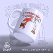 Чашка Сама собі свято, біла, зображена з правого боку, на фоні світло-фіолетового кольору, з кольоровим принтом, що містить напис "САМА СОБІ СВЯТО!" та малюнок дівчинки, ручка кругла, край рівний, глянцева поверхня.
