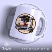 Чашка сувенір на випускний, біла, зображена в ракурсі зліва, на фоні світло-фіолетового кольору, принт містить зображення диплома та капелюха випускника, напис чорного кольору, ручка класична, край рівний, глянцева поверхня.