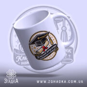 Чашка сувенір на випускний, біла, зображена в ракурсі справа, на фоні світло-фіолетового кольору, принт містить зображення диплома та капелюха випускника, напис чорного кольору, ручка класична, край рівний, глянцева поверхня.