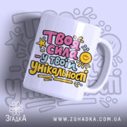 Чашка Сила в твоїй унікальності. Чашка білого кольору з яскравим принтом на передній частині, що містить текст у рожевому, жовтому та блакитному кольорах. Ручка чашки гладка, край рівний, поверхня глянцева. Фон з легким градієнтом, що підкреслює кольори принта.