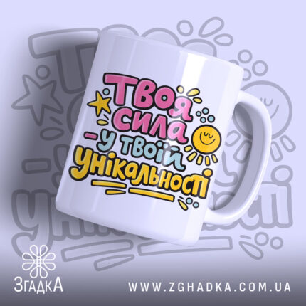 Чашка Сила в твоїй унікальності. Чашка білого кольору з яскравим принтом на передній частині, що містить текст у рожевому, жовтому та блакитному кольорах. Ручка чашки гладка, край рівний, поверхня глянцева. Фон з легким градієнтом, що підкреслює кольори принта.