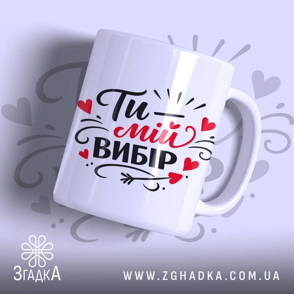Чашка Ти – мій вибір, біла з яскравим чорним і червоним принтом, показана з бокового ракурсу на світло-сірому фоні, з написом "Ти – мій вибір" та декоративними елементами у вигляді сердечок, має гладку ручку та рівний край, з глянцевою поверхнею.