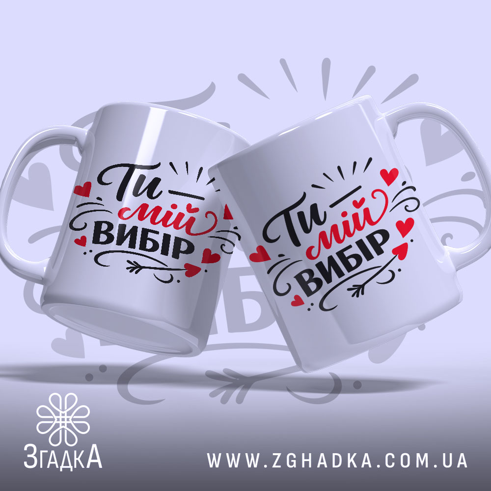 Чашка Ти – мій вибір, дві білі чашки з однаковим принтом, показані під кутом на світло-сірому фоні, з написом "Ти – мій вибір" в чорному і червоному кольорах, обидві чашки мають гладкі ручки та рівні краї, з глянцевою поверхнею.