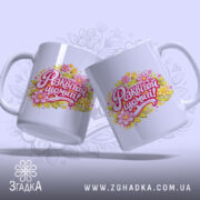 Чашка жіноча Розквітай щомиті, дві білих чашки з кольоровим принтом, на якому написано 'Розквітай щомиті!' з квітами, ручки округлі, край рівний, глянцевий фініш, фон світло-фіолетовий з легким малюнком.