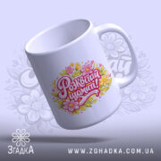 Чашка жіноча Розквітай щомиті, біла з кольоровим принтом, на якому написано 'Розквітай щомиті!' з квітами, ручка округла, край рівний, глянцевий фініш, фон світло-фіолетовий з легким малюнком.