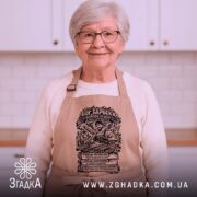 Фартух Бог барбекю, бежевого кольору, зображений з фронтального ракурсу на нейтральному фоні, принт з написом та малюнком барбекю на чорному фоні.