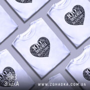 Футболка 100% любові всередині, біла, зображена на чоловікові, ракурс спереду, фон світло-фіолетовий, принт у формі серця чорного кольору з написом "100% любові всередині" в декоративному шрифті.