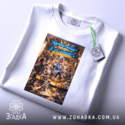 Футболка адміністрація мами, біла, на столі, фон світло-сірий, принт з ілюстрацією жінки в блакитному халаті, яка подає їжу, текст на принті українською мовою, на комірці є етикетка.