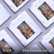 Футболка адміністрація мами, біла, на моделі, фон світло-сірий, принт з ілюстрацією жінки в блакитному халаті, яка подає їжу, навколо діти і кішка, текст на принті українською мовою.