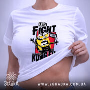 Футболка Бій з кунг-фу, біла, на столі, з верхнього ракурсу, фон світло-фіолетовий, принт з жовтим персонажем у чорному одязі, текстом 'LET'S FIGHT WITH KUNGFU SOUNDS!!!' на червоному фоні, з етикеткою.