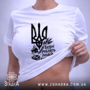 Футболка будні роблять людей буденними. Біла футболка, зображена на плоскій поверхні, фон світло-сірий. Принт чорного кольору з тризубом та написом 'Будні роблять людей буденними'. На футболці видно етикетку з зеленим шнурком.