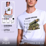 Футболка будова черепахи, біла, зображена на молодому чоловікові, фон світло-фіолетовий, принт з черепахою, що має на спині ракетну установку, текст на українській мові.