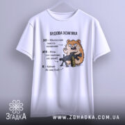 Футболка будова хомʼяка, біла, підвішена на вішалці, фон світло-сірий, принт з хомʼяком, що тримає гвинтівку, текст з характеристиками хомʼяка.