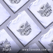 Футболка час розправляти крила, біла, зображена на молодому чоловікові, який позує на нейтральному фоні, принт з крилами та написом в стилі вінтаж, чорний текст на білому фоні.