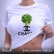 Футболка Chavel Bazar білого кольору, складена на поверхні, ракурс зверху, фон світло-фіолетовий, принт з зображенням пучка шпинату та логотипом CHAVEL BAZAR під ним, з біркою на шнурку.