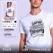 Футболка дарую щастя щодня, біла, на моделі з легким ракурсом, фон ніжно-фіолетовий, принт чорного кольору з написом та елементами декору.