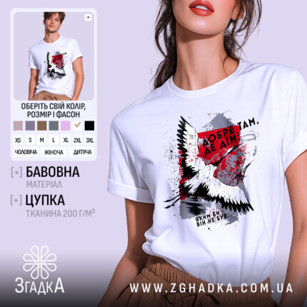Футболка добре там де дім. Біла футболка на моделі, з принтом на грудях, що містить зображення птаха та текст. Фон світло-фіолетовий, модель позує з легким усмішкою, підкреслюючи стиль футболки.