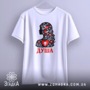 Футболка Душа український стиль, біла, підвішена на вішалці, фон світло-сірий, принт з силуетом жінки, прикрашеним червоними пташками та квітами, текст 'ДУША' червоним кольором.
