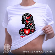 Футболка Душа український стиль, біла, складена на поверхні, фон світло-сірий, принт з силуетом жінки, прикрашеним червоними пташками та квітами, текст 'ДУША' червоним кольором, на етикетці зелена стрічка.