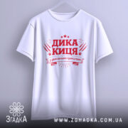 Футболка дика киця білого кольору, підвішена на вішалці, фон світло-сірий, принт червоного кольору з написом 'ДИКА КИЦЯ' та декоративними елементами.