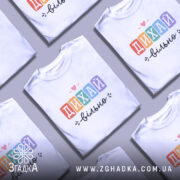 Футболка дихай вільно, біла, зображена на моделі в ракурсі спереду, фон світло-фіолетовий, принт з написом 'ДИХАЙ вільно' у кольорових квадратах, з сердечком над словом 'ДИХАЙ'.