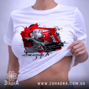 Футболка Джозеф Конрад, біла, складена на поверхні, фон світло-сірий, принт з червоними та чорними елементами, зображення чоловіка та текст, на етикетці зелена стрічка.