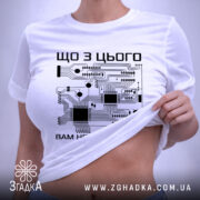 Футболка електрична схема, біла, зображена на плоскій поверхні, фон світло-сірий, принт з чорними елементами електронної схеми та текстом на українській мові, на комірці є етикетка.