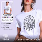 Футболка гори лікують. Біла футболка з коротким рукавом, зображена на моделі, фон світло-фіолетовий, принт з горами та текстом чорного кольору.