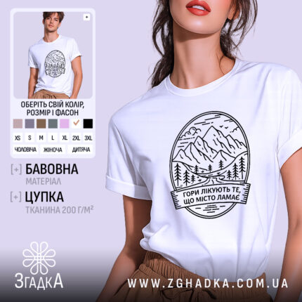 Футболка гори лікують. Біла футболка з коротким рукавом, зображена на моделі, фон світло-фіолетовий, принт з горами та текстом чорного кольору.