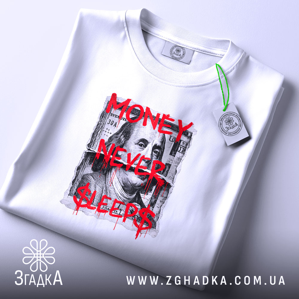 Футболка Гроші не сплять, біла, складена на поверхні, ракурс зверху, фон світло-сірий, принт з написом 'MONEY NEVER $LEEPS$' червоного кольору на фоні зображення купюри, з етикеткою зеленого кольору.