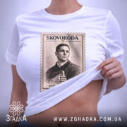 Футболка Григорій Сковорода, біла, зображена на столі, ракурс зверху, фон світло-сірий, принт у вигляді поштової марки з портретом Григорія Сковороди та написом 'SVIT LOVYV MENE', на футболці є етикетка.