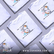 Футболка Я не подарунок. Біла футболка на молодому чоловікові, зображена в анфас, фон світло-фіолетовий. Принт з ведмедиком, який тримає кульки, з написом українською мовою.