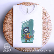 Футболка я вас навчу: біла футболка, розкладена на плетеній кошику, принт пірата добре видно, фон світло-сірий, ракурс зверху, деталі принта кольорові.