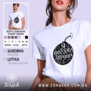 Футболка я вибухова дівчина, біла, зображена з ракурсу спереду на моделі, фон світло-фіолетовий, принт чорного кольору у формі бомби з написом 'Я ВИБУХОВА ДІВЧИНА'.