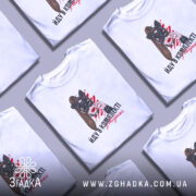 Футболка йду в комплекті з валідолом, біла, зображена на моделі з коротким рукавом, фон світло-фіолетовий, принт з жінкою в масці кота з червоними мазками на фоні та написом.