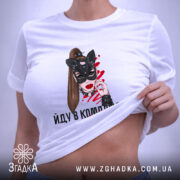 Футболка йду в комплекті з валідолом, біла, зображена на плоскій поверхні, фон світло-фіолетовий, принт з жінкою в масці кота, написом і етикеткою з зеленим шнурком.