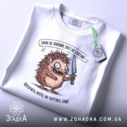 Футболка Їжак не ніжний, біла, зображена в горизонтальному положенні, фон світлий, принт з їжаком з ножем, текст зверху принта, на футболці є етикетка.