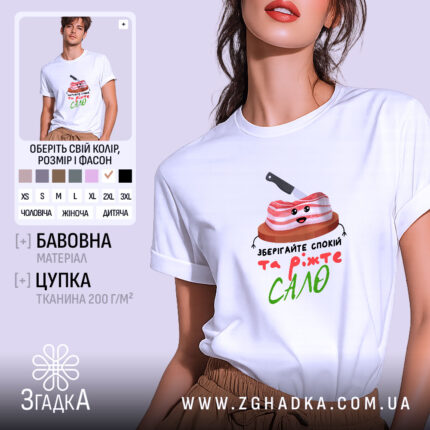 Футболка Їжте сало, біла, зображена на моделі, яка позує з легким усмішкою, фон м'який пастельний, принт з веселим шматком сала на дерев'яній дошці з ножем, текст під принтом написаний кольоровими літерами.