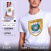 Футболка карпати в серці, біла, на моделі, з принтом у вигляді герба, що містить зображення гір, будинку та напис 'КАРПАТИ В СЕРЦІ СПОКІЙ У ГОЛОВІ', фон ніжно-фіолетовий.