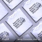 Футболка хочу стати котом. Біла футболка на чоловікові, зображена з близької відстані, фон світло-фіолетовий. Принт чорного кольору з котом, який сидить на грошах, з текстом "Рівень стресу: хочу стати котом багатих людей".