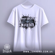 Футболка Храм святого Мавіка, біла, підвішена на вішалці, фон світло-сірий, принт з чорними плямами та написом 'Храм святого Мавіка'.