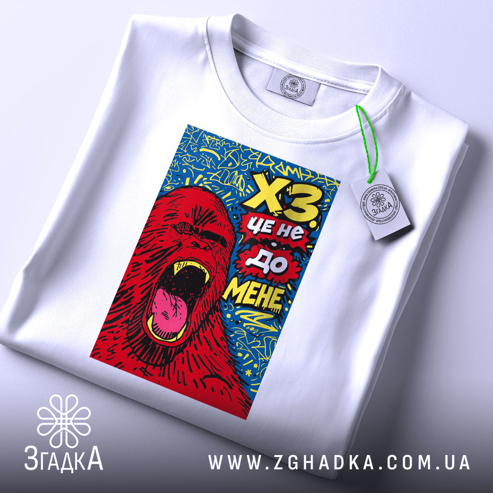 Футболка ХЗ білого кольору, зображена зверху, фон світлий, принт з червоним ведмедем, що кричить, на синьому фоні, з зеленим ярликом.