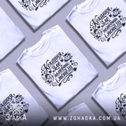 Футболка Кохання зле, біла, зображена на моделі в ракурсі спереду, фон світло-фіолетовий, принт чорного кольору з малюнками ангела та диявола, текстом "Кохання зле, полюбиш і мене".