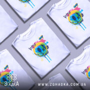 Футболка Кольоровий поп арт, біла, на моделі з легким усмішкою, фон світлий, принт з кольоровим смайлом та написом 'WOW', яскраві кольори: жовтий, зелений, блакитний, рожевий, чорний.