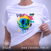 Футболка Кольоровий поп арт, біла, на столі, ракурс зверху, фон світлий, принт з кольоровим смайлом та написом 'WOW', яскраві кольори: жовтий, зелений, блакитний, рожевий, чорний, етикетка з зеленим шнурком.